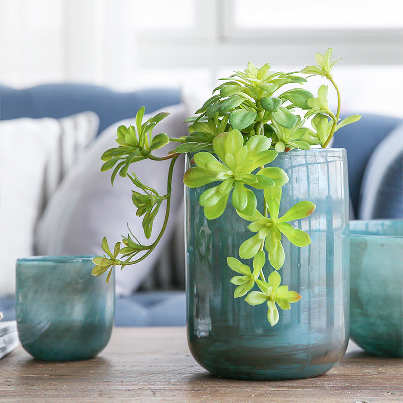 Azurblaue Vase mit schöner Bepflanzung auf einem Couchtisch im Wintergarten